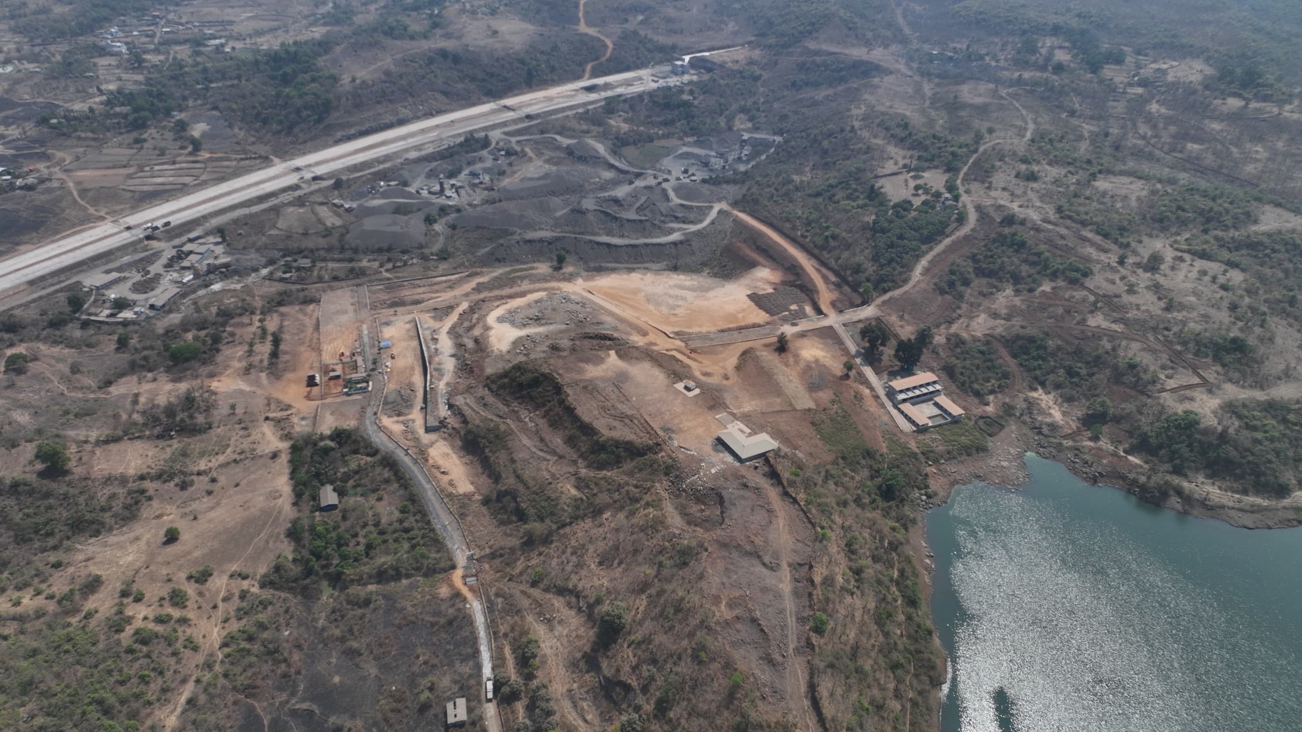 Aerial photograph of the project land from the north-west, with the site buildings at centre, the lake to the right and the highway running along the top of the frame.
